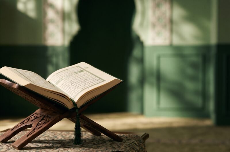 مصحف مفتوح على حامل خشبي في إضاءة هادئة، تعبيراً عن دراسة القراءات القرآنية